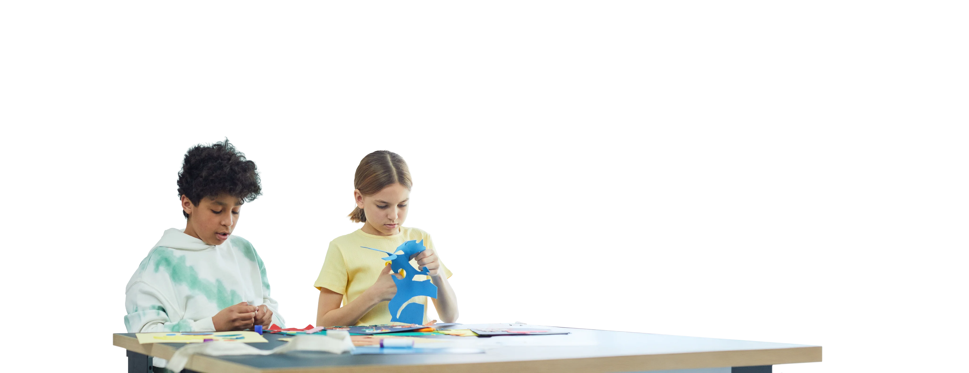Children engaged in arts and crafts, focusing on colorful paper cutouts at a table.