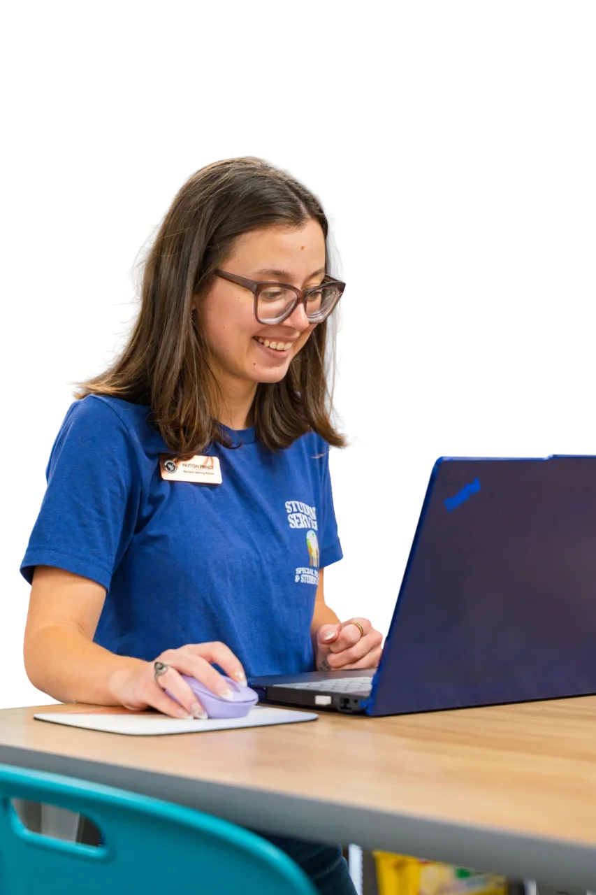 Smiling woman wearing a "Student Services" shirt works on a laptop, enhancing user engagement.