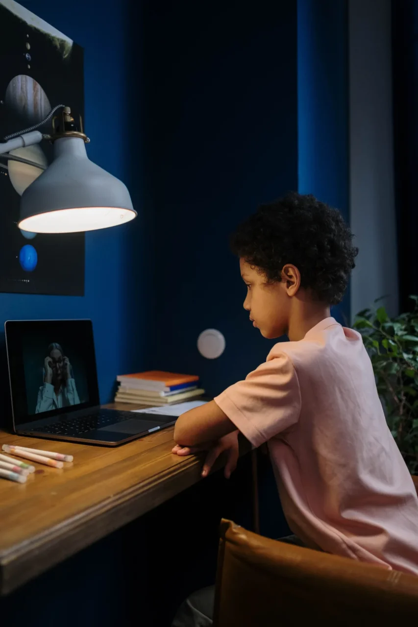 Child engaged in virtual learning on laptop, highlighting Cyber Academy's in-person support for students.