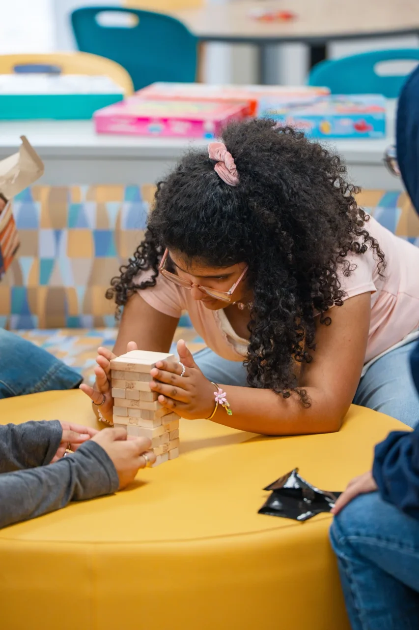 Student engaging in a structured activity with a Jenga tower, promoting academic support in the virtual school community.