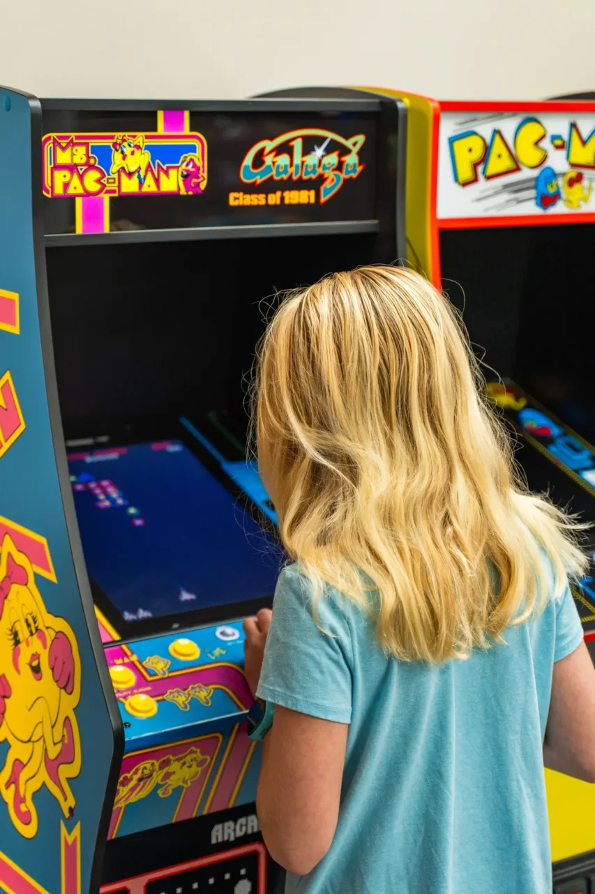 Child playing an arcade game, Ms. Pac-Man, showcasing interactive learning at Hill supports virtual academy.