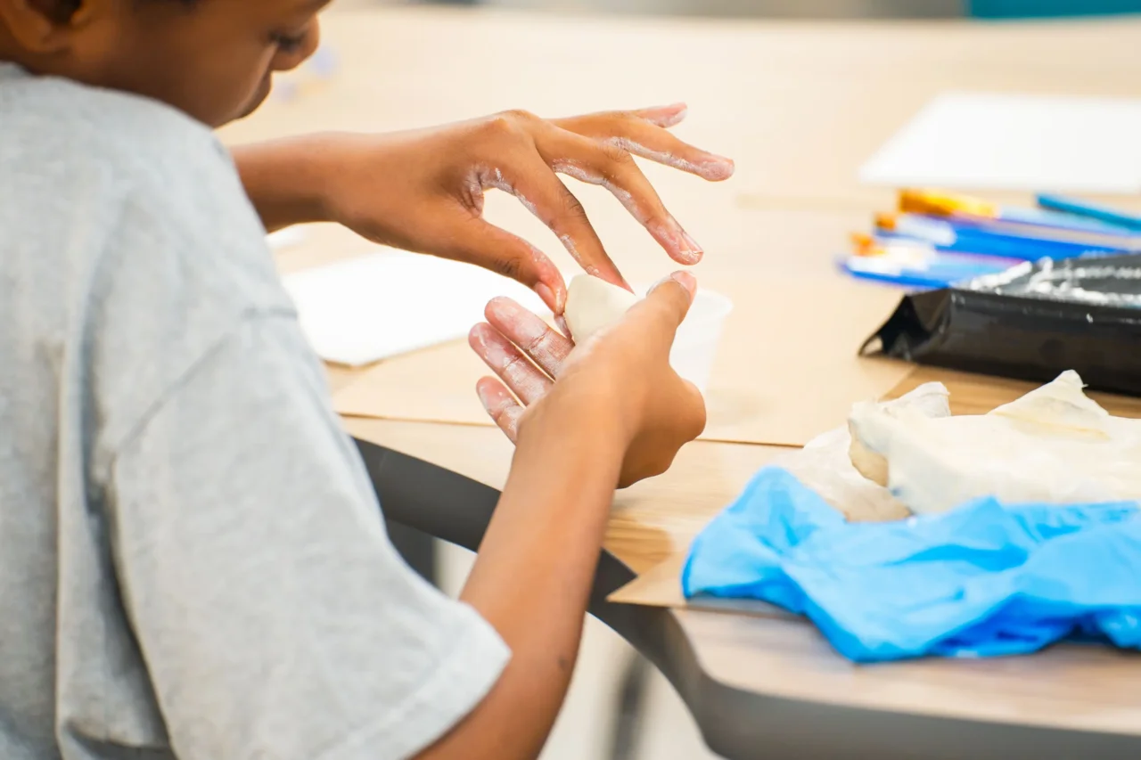 Student crafting clay model at Cyber Academy, person support available to every student for connection.