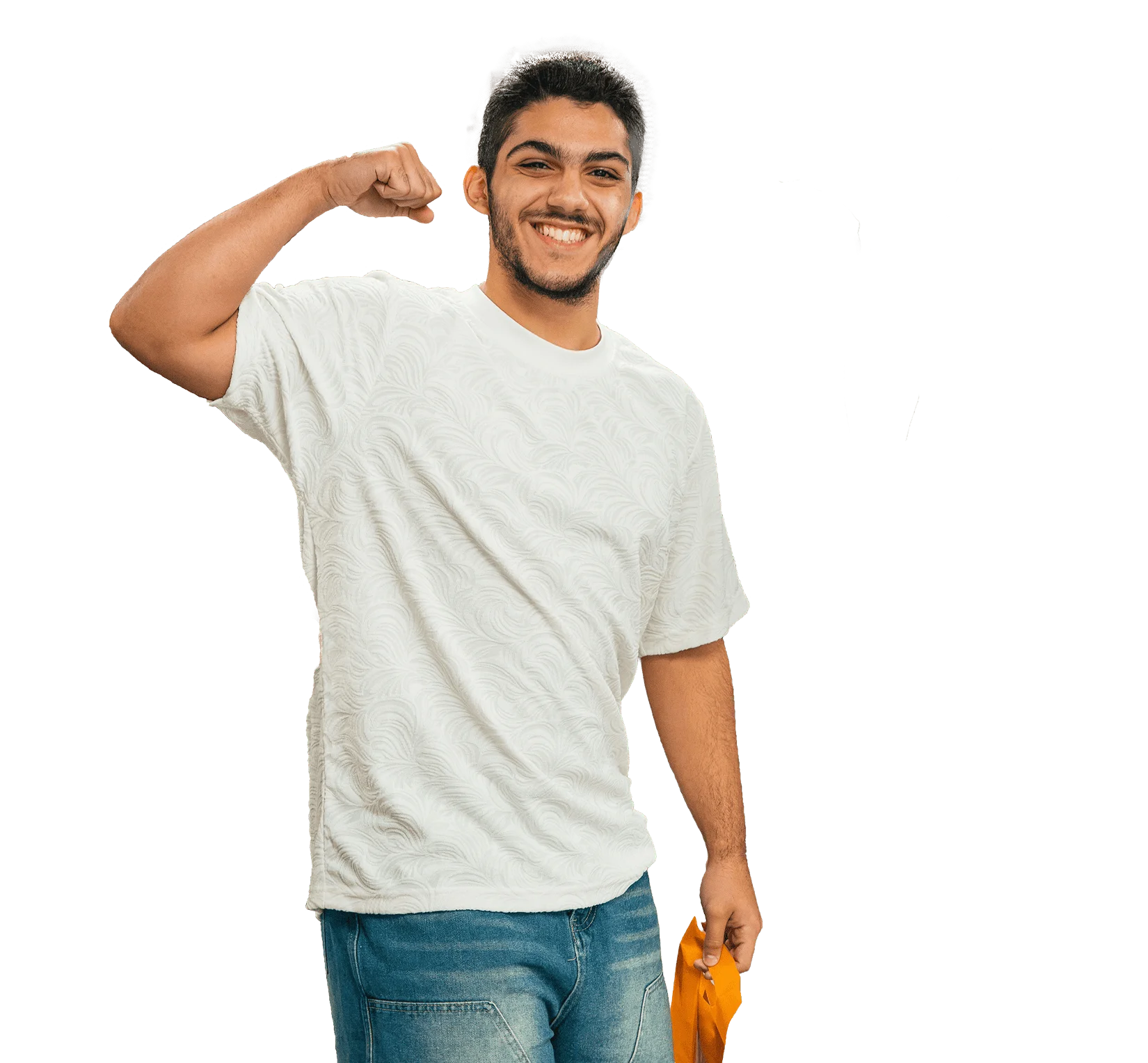 Smiling man in white t-shirt flexing bicep, holding a yellow bag, wearing jeans against green background.